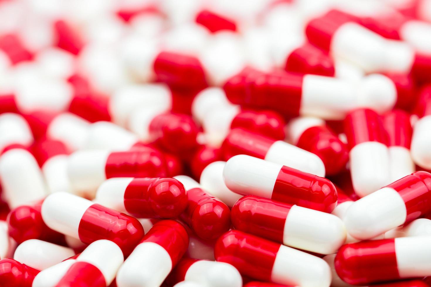 Pile of red-white antibiotic capsule pills. Prescription drugs. Pharmaceutical industry. Antibiotic drug resistance. photo