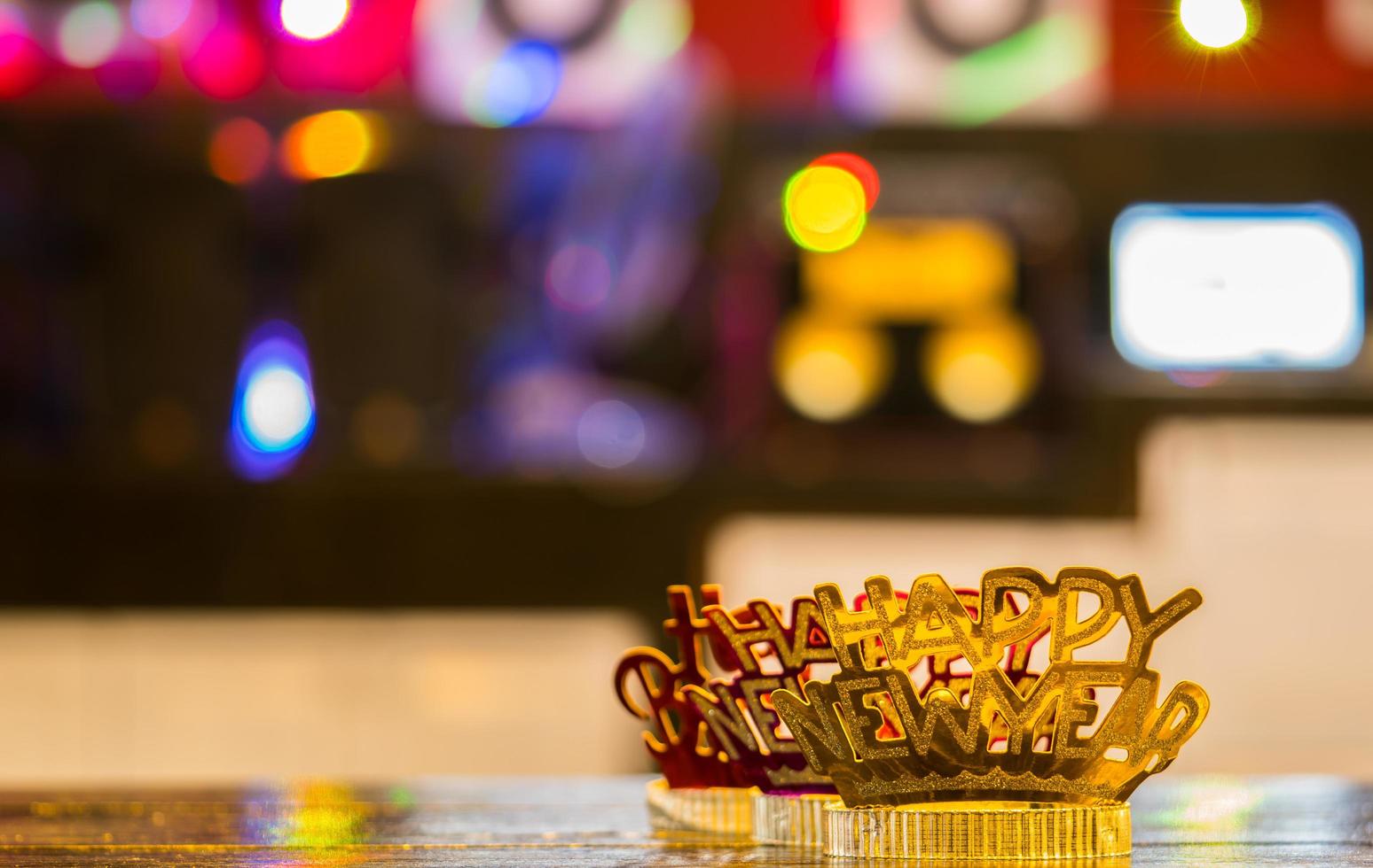 Diadema de feliz año nuevo rojo dorado sobre fondo colorido bokeh foto