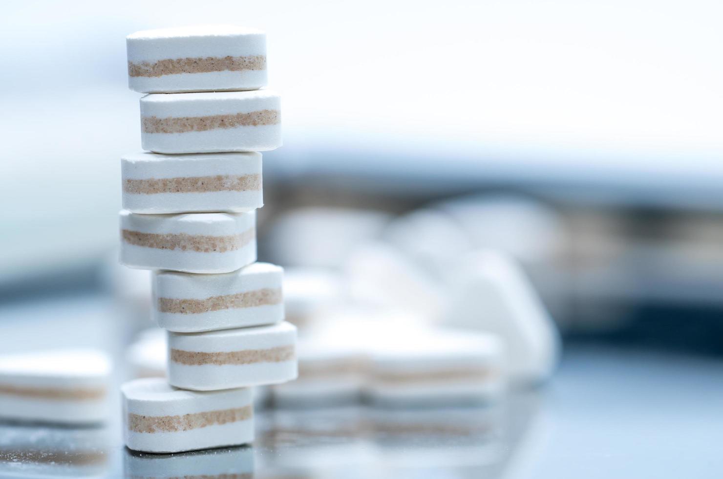 Macro shot of triangle shape tablet pills. Three layers tablet pills for indication antacid, digestive and gastric pain. Group of sandwich tablets pills on white background with copy space for text. photo