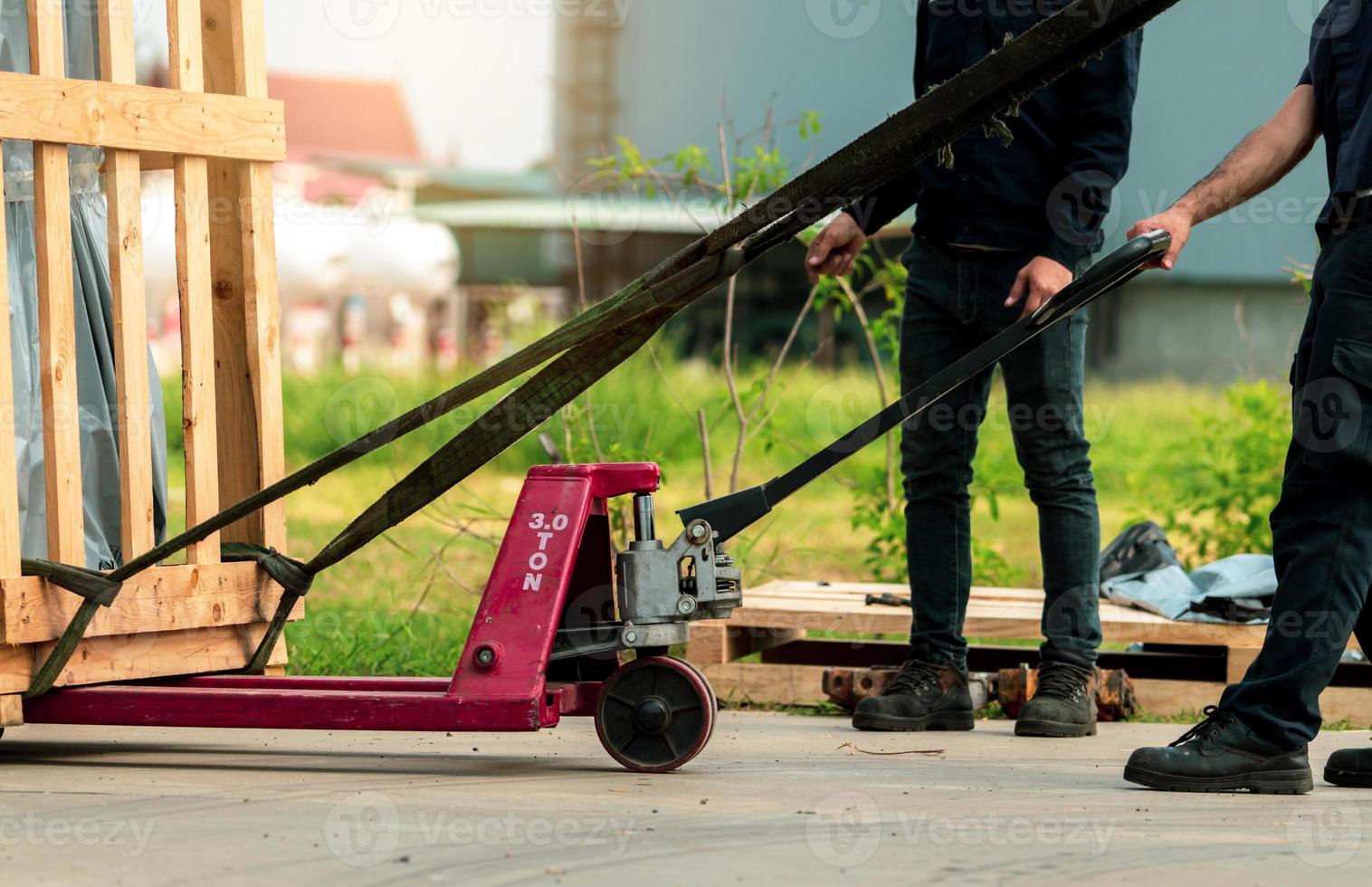 Worker working with hand pallet forklift stacker to delivery machine in wooden box to factory warehouse. Freight transport. Heavy goods transport. Warehouse and shipping business. Unloading from truck photo