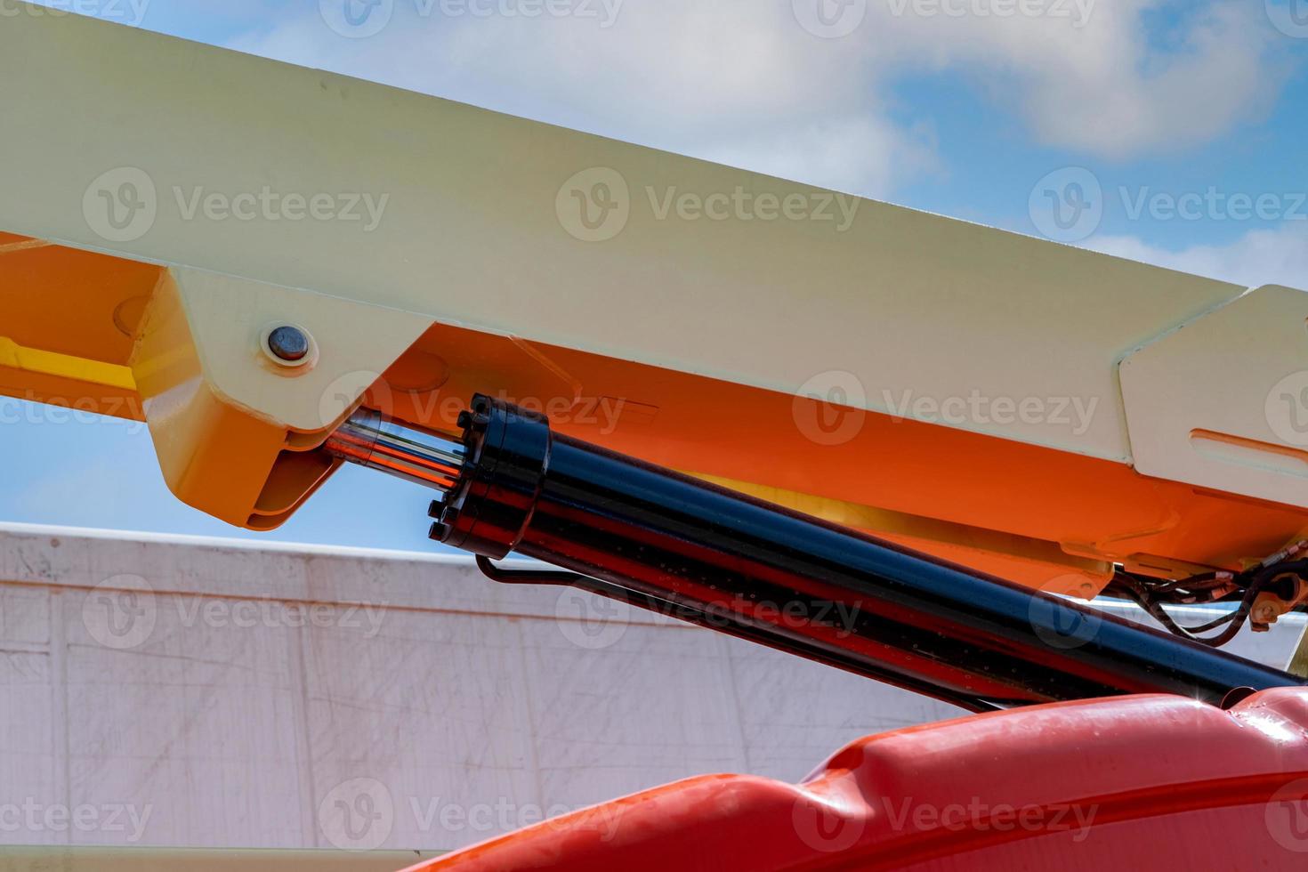 Closeup hydraulic of boom lift. Orange articulated boom lift. Maintenance and repair hydraulic boom lift service. Aerial platform. Telescopic boom lift. Mobile construction crane. Hydraulic cylinder. photo