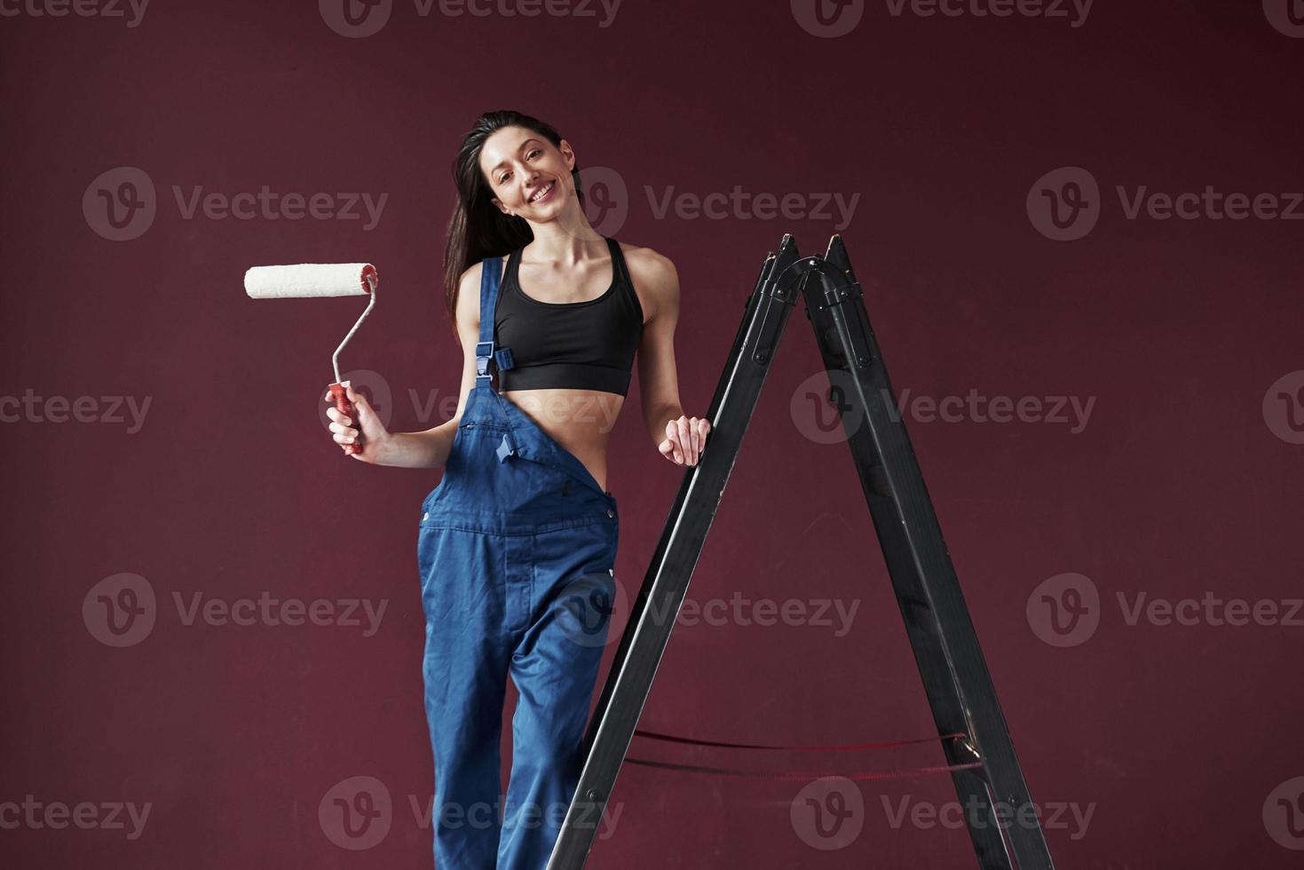 sonriendo para la cámara. joven ama de casa decidió pegar papel tapiz en su nueva casa en la habitación foto