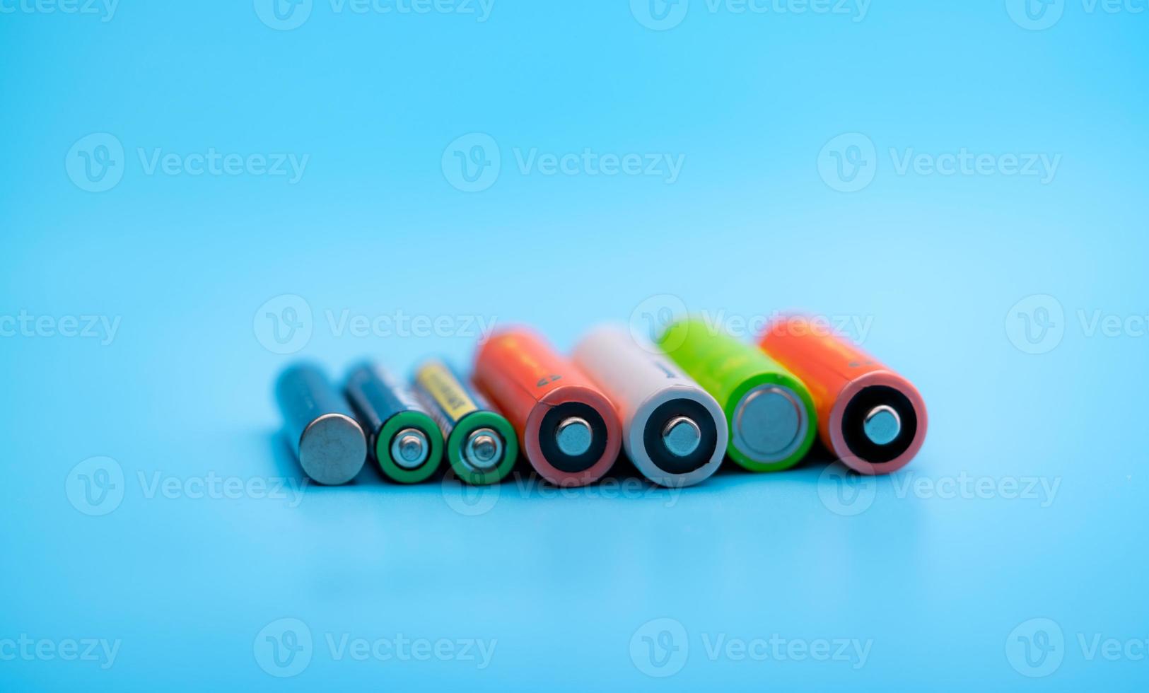 Rechargeable battery on blue background. Positive and negative terminals of rechargeable lithium-ion batteries. AA and AAA size of old Li-ion battery. Battery recycling concept. Green power energy. photo