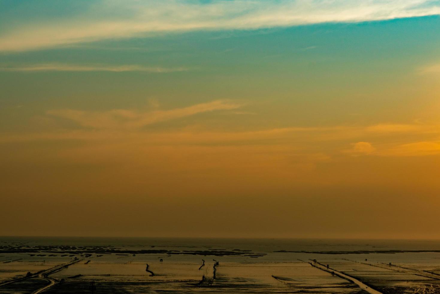 Orange and blue sunset sky and clouds. Sunset at the beach. Mud beach at seashore. Beautiful skyline at dusk. Landscape of muddy beach with golden sky. Tranquil and peaceful background. Love the earth photo