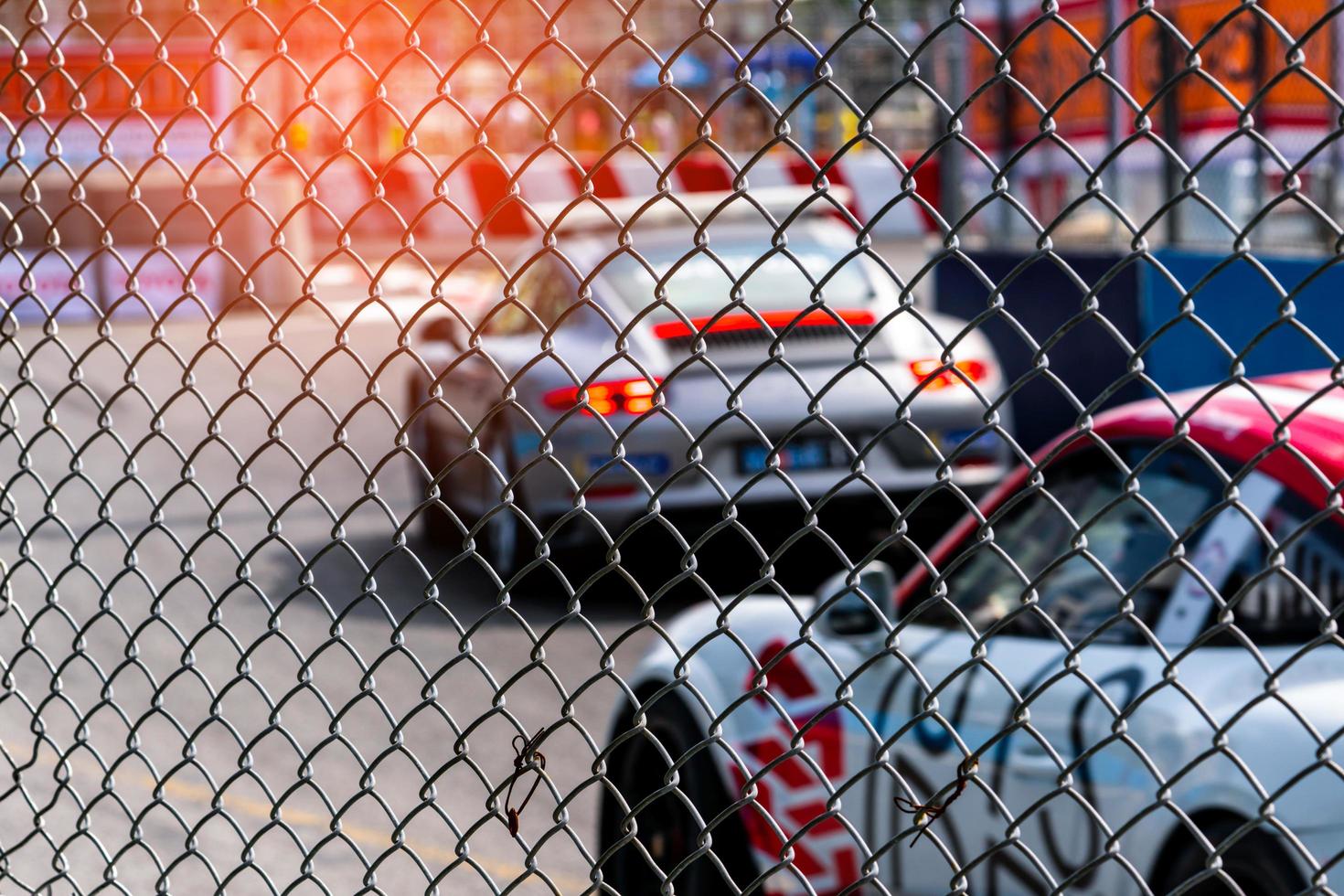 Motorsport car racing on asphalt road. View from the fence mesh netting on blurred car on racetrack background. Super racing car on street circuit. Automotive industry concept. photo