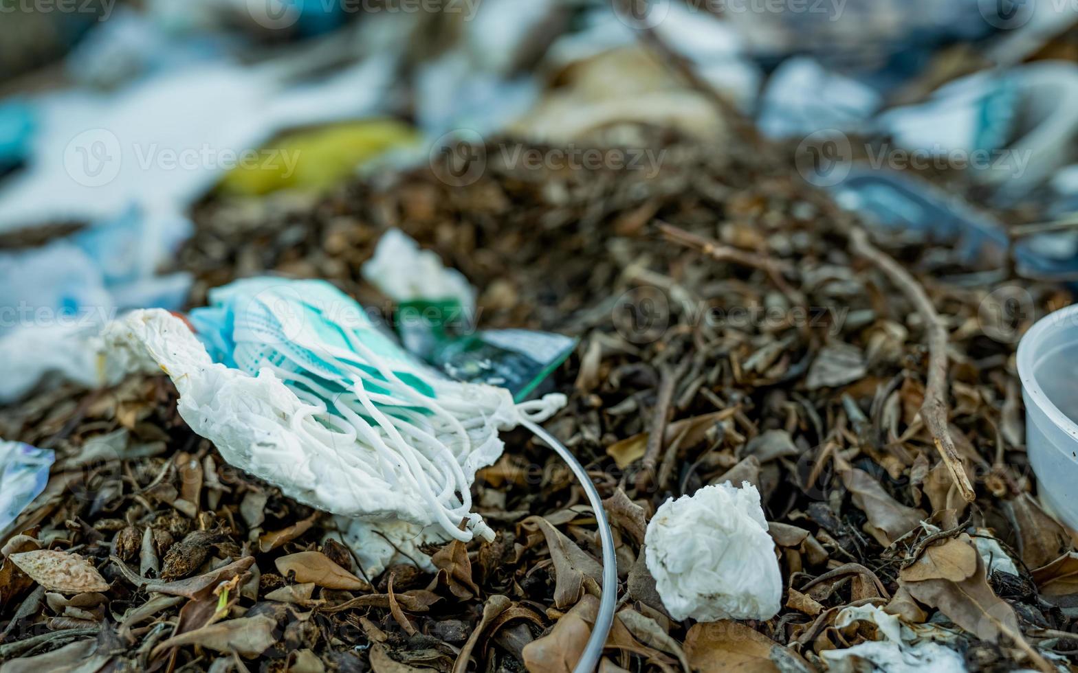 deseche la máscara facial usada en la basura doméstica. eliminación de desechos médicos con manejo antihigiénico. residuos contaminados en la comunidad. Mascarilla desechable con gancho para la oreja Basura de residuos en el suelo. impacto del coronavirus foto