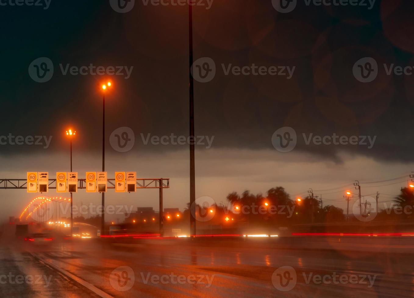 Street light at night in rainy day. Car and truck on asphalt road. Dark night at highway with electric lamp light and speed limit traffic sign and camera speed symbols. Red street light and dark sky. photo