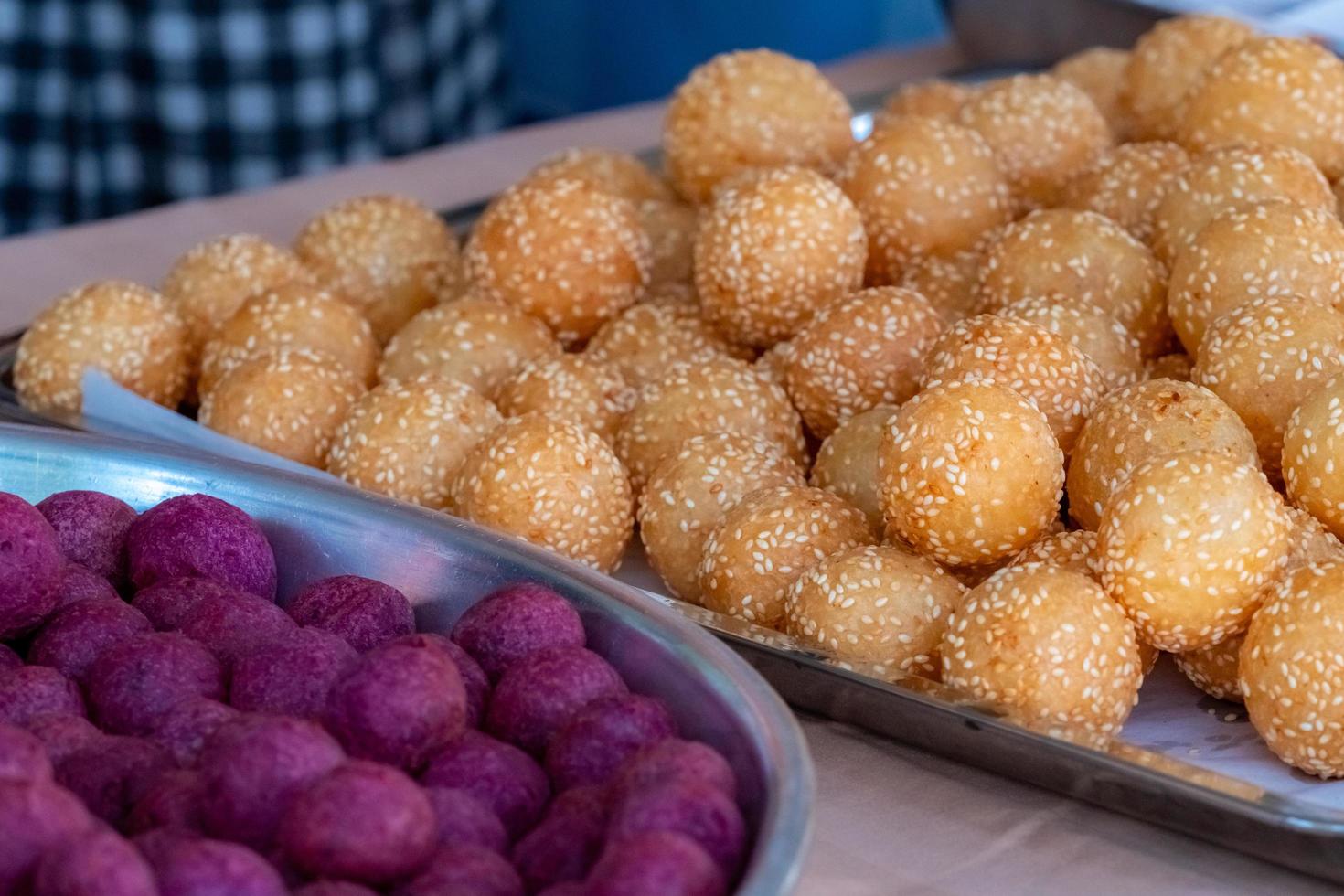 Thai traditional dessert. Deep fried sesame balls and deep fried sweet potato balls on stainless steel tray of seller. Purple and brown sweets balls. photo