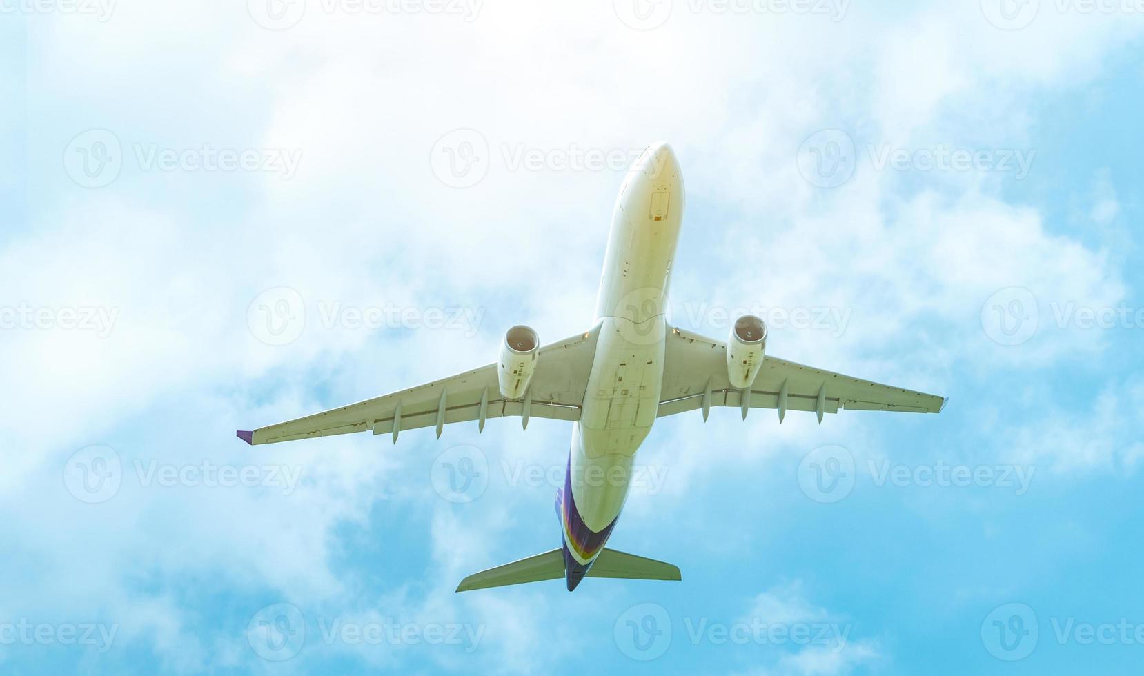 Commercial airline flying on blue sky and white fluffy clouds. Under view of airplane flying. Passenger plane after take off or going to landing flight. Vacation travel abroad. Air transportation. photo