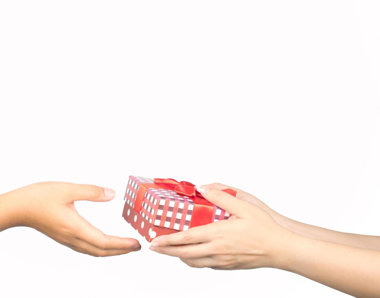 Closeup hands giving and receiving Christmas gift box wrapped with red ribbon isolated on white background photo