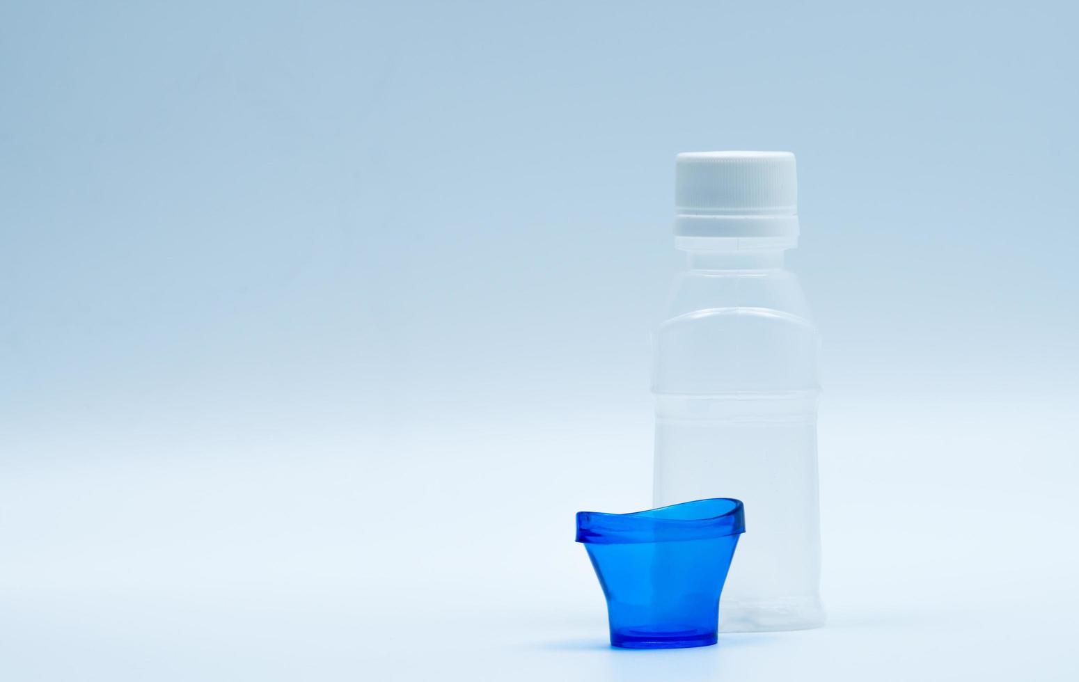 loción ocular estéril en botella de plástico blanco con baño de ojos azul y espacio de copia y etiqueta en blanco. lavado de ojos después de la contaminación del contacto con el medio ambiente o después de nadar en una piscina contaminada con cloro. foto