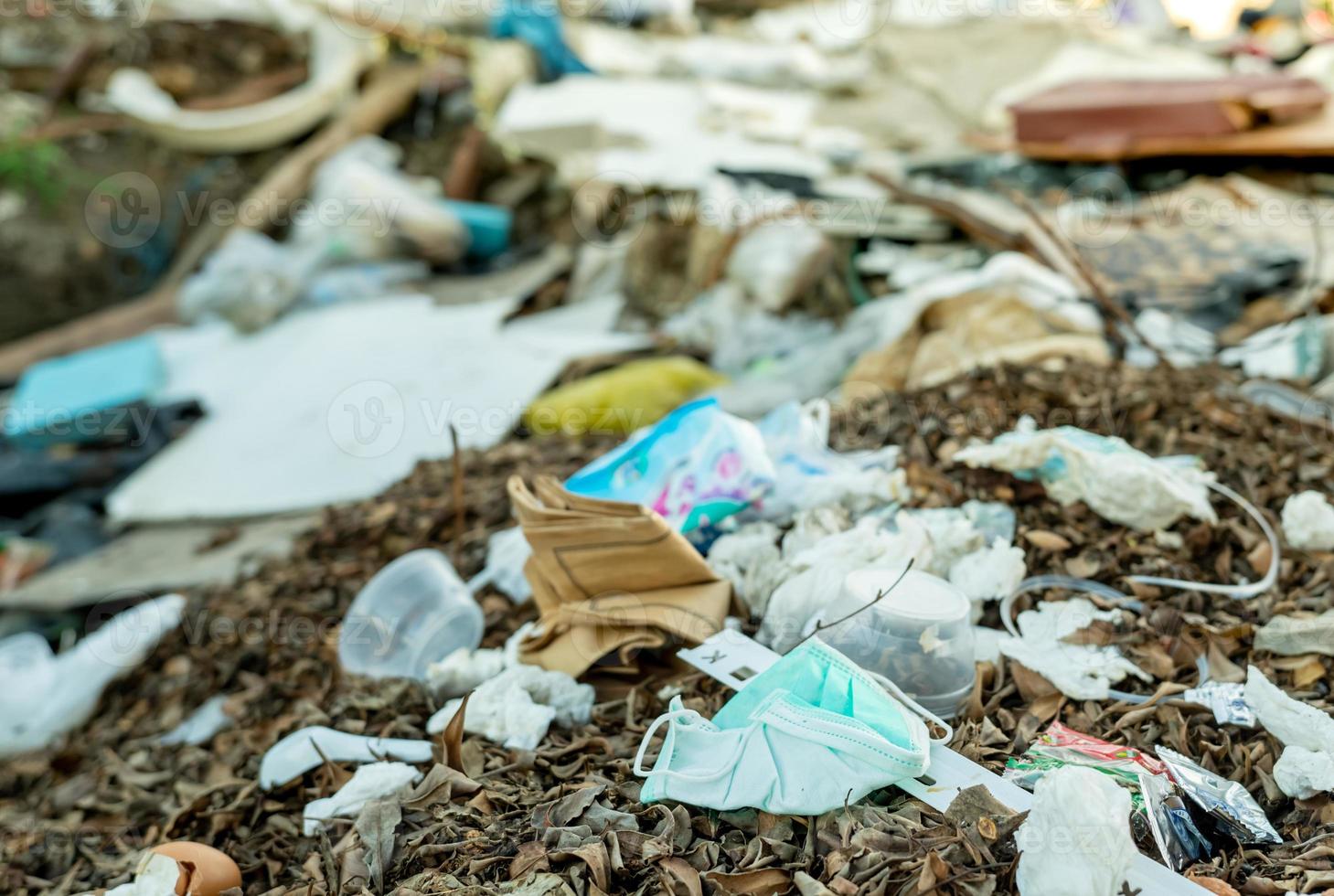 deseche la máscara facial usada en la basura doméstica. eliminación de desechos médicos con manejo antihigiénico. residuos contaminados en la comunidad. Mascarilla desechable con gancho para la oreja Basura de residuos en el suelo. impacto del coronavirus foto