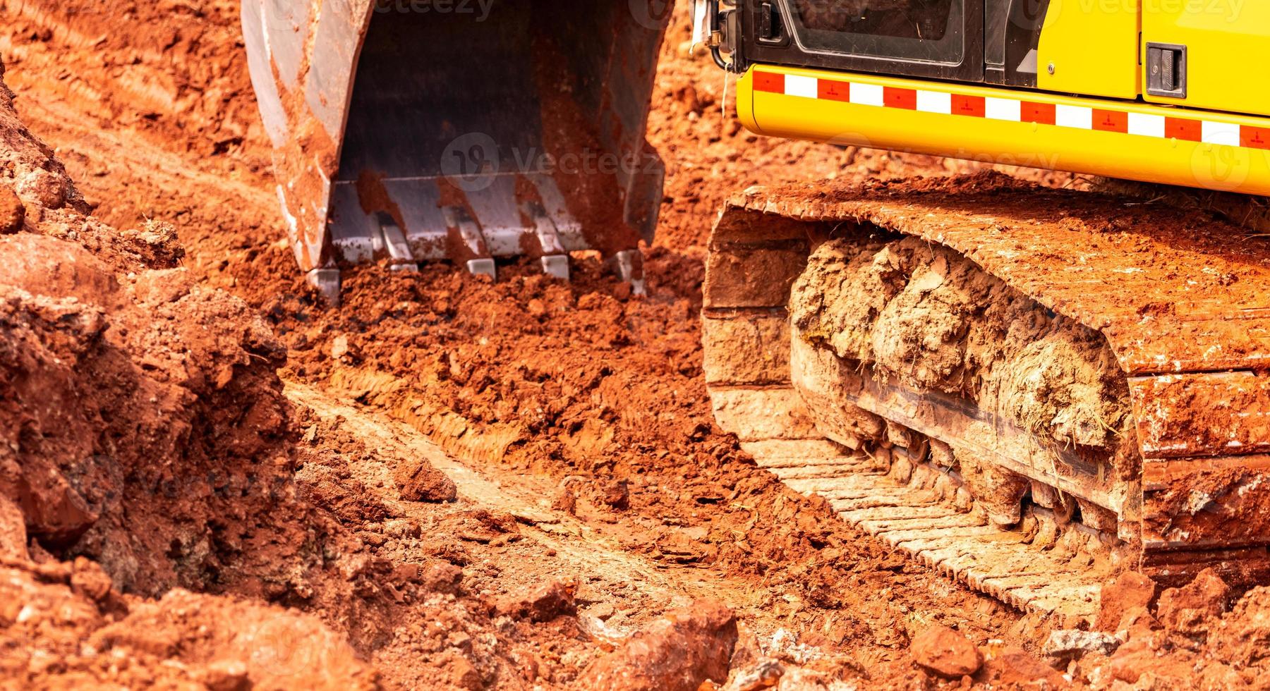 Backhoe working by digging soil at construction site. Bucket of backhoe digging soil. Crawler excavator digging on dirt. Excavating machine. Earth moving machine. Excavation vehicle. Trenching machine photo