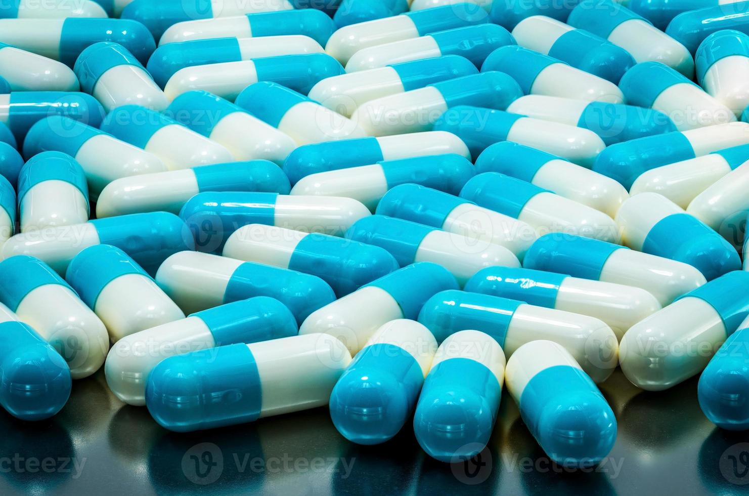 Blue-white antibiotic capsule pill spread on stainless steel drug tray. Global healthcare concept. Antibiotics drug resistance. Antimicrobial capsule pills. Pharmaceutical industry. Capsule texture. photo