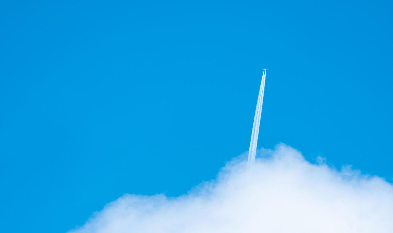 Airplane with white condensation tracks. Jet plane on blue sky and white clouds with vapor trail. Travel by airplane concept. Trails of exhaust gas from airplane engine. Aircraft with white stripes. photo