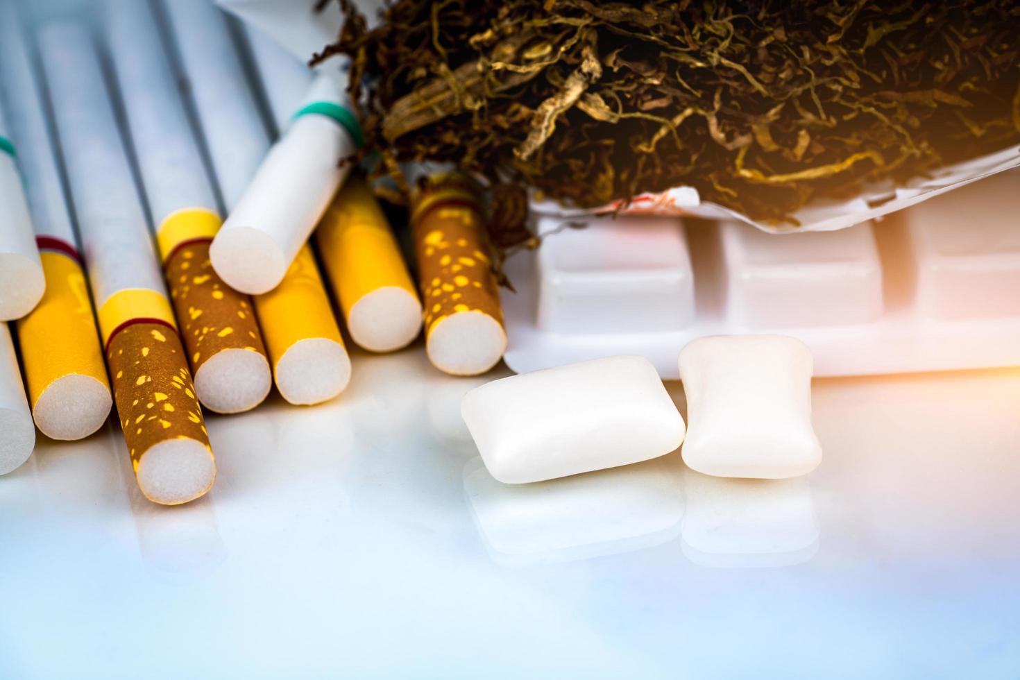 Nicotine chewing gum near pile of cigarettes and tobacco on white background with space. Quit smoking or smoking cessation and lung cancer concept. 31 May World no tobacco day. photo