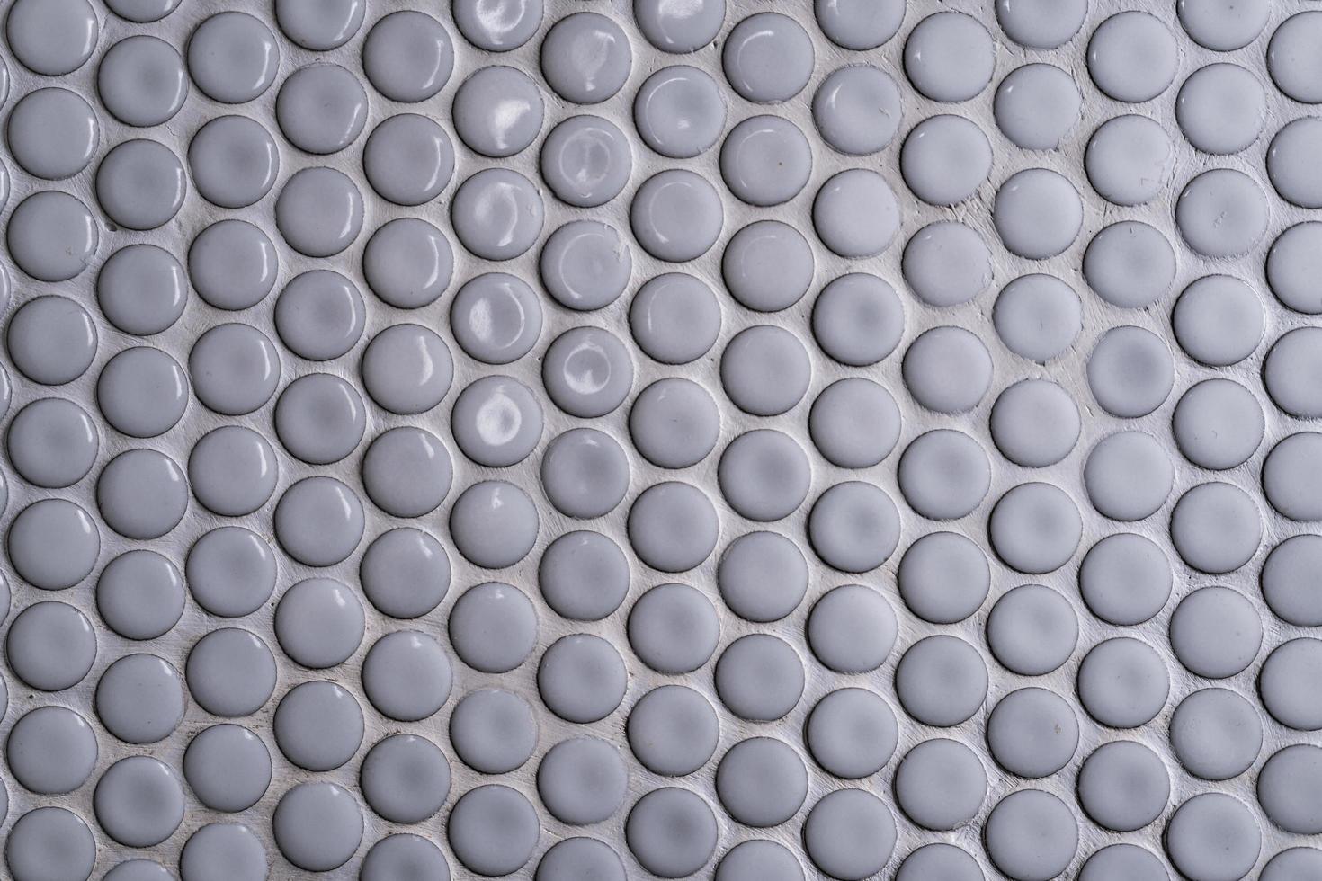 White ceramic tile wall with many small round unique pattern. Top view of bathroom wall tile is a round button tile. Circle white mosaic tile abstract texture background. photo