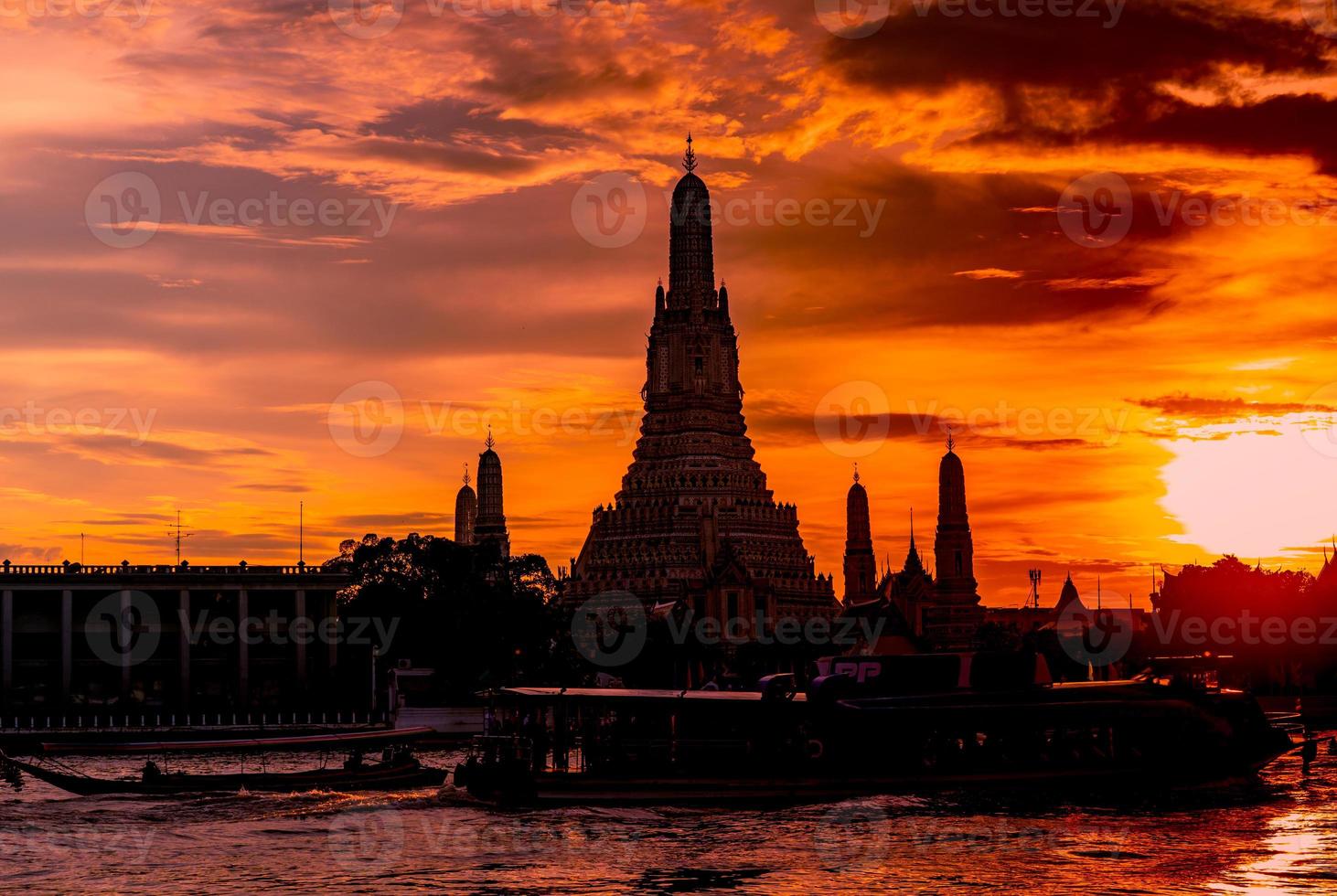 wat arun ratchawararam al atardecer con hermoso cielo rojo y naranja y nubes. el templo budista wat arun es el punto de referencia en bangkok, tailandia. arte de atracción silueta espectacular cielo y templo. foto