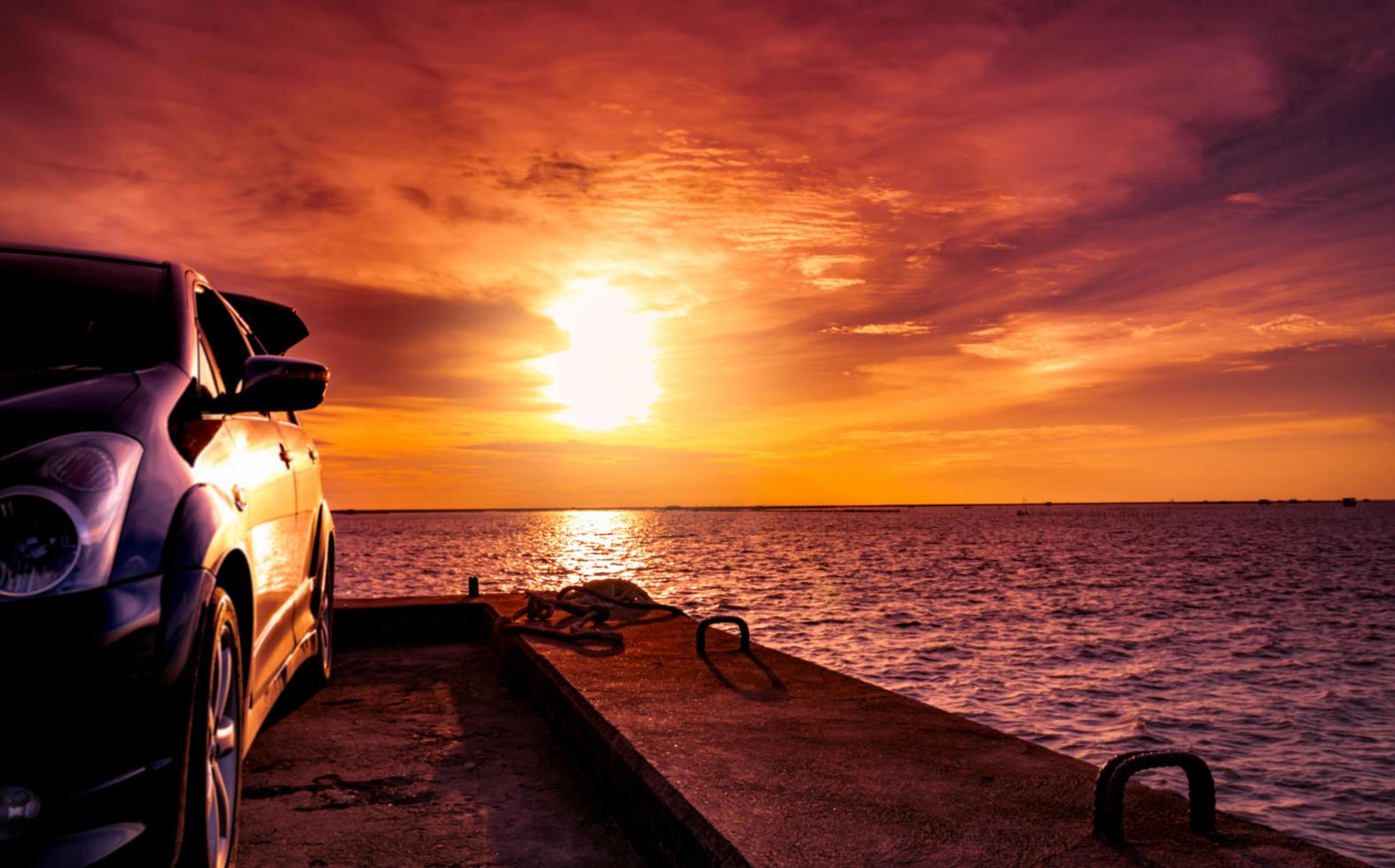 SUV car with sport and modern design parked on concrete road by the sea at sunset. Electric car technology. Hybrid auto and automotive. Road trip travel on vacation at the beach. Rope on concrete. photo