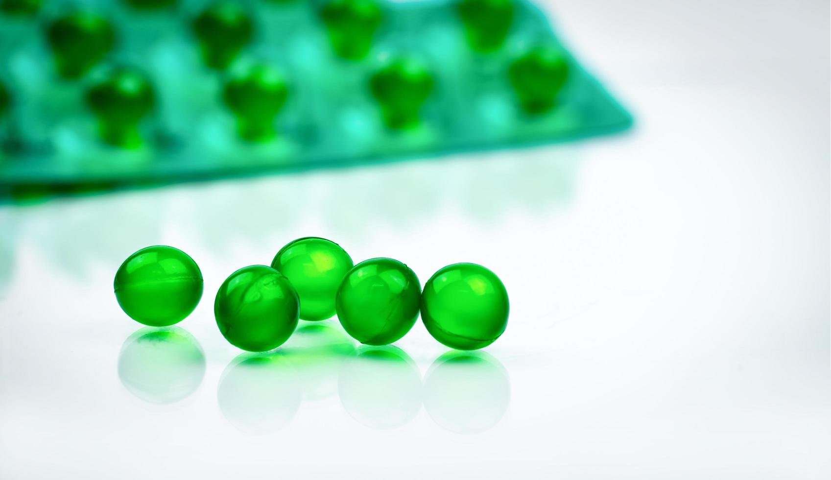 Green round soft capsule pills on blurred background of blister pack with space. Ayurvedic medicine for indigestion, gas and acidity. Herbal medicine made from Mentha oil and spearmint oil from India photo