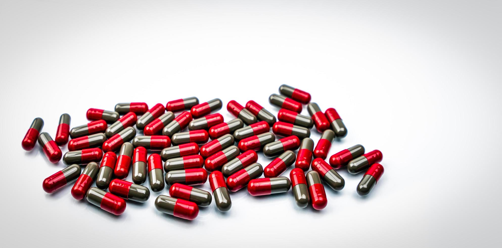 Pile of red-gray capsule pills on white background. Pharmaceutical industry. Pharmacy drugstore product. Pharmaceutical manufacturing. Pharmaceutics. Global healthcare concept. Many of capsule pills. photo