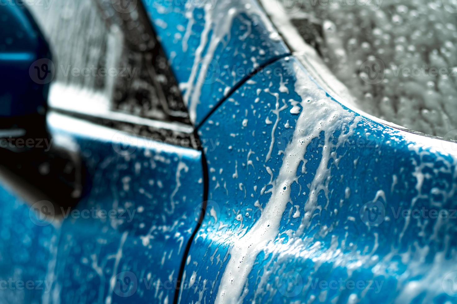 Blue car wash with white soap foam. Auto care business. Car cleaning and shining before waxing service. Vehicle cleaning service with antiseptic and disinfection of coronavirus COVID-19. Carwash. photo