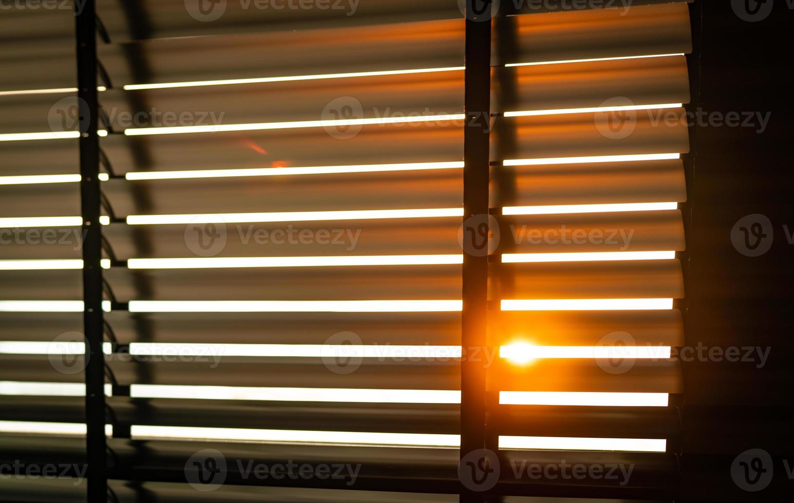 Opened venetian plastic blinds with sunlight in the morning. White plastic window with blinds. Interior design of living room with window horizontal blinds. Window slatted shades made of plastic. photo