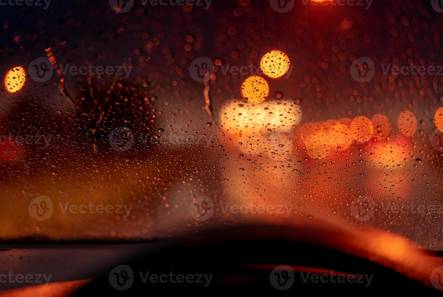 Orange night light bokeh from street light on traffic jam day. Rainy day. Transparent glass window with rain drop. Romantic weather. City life. Blur abstract background of urban light on rainy season photo