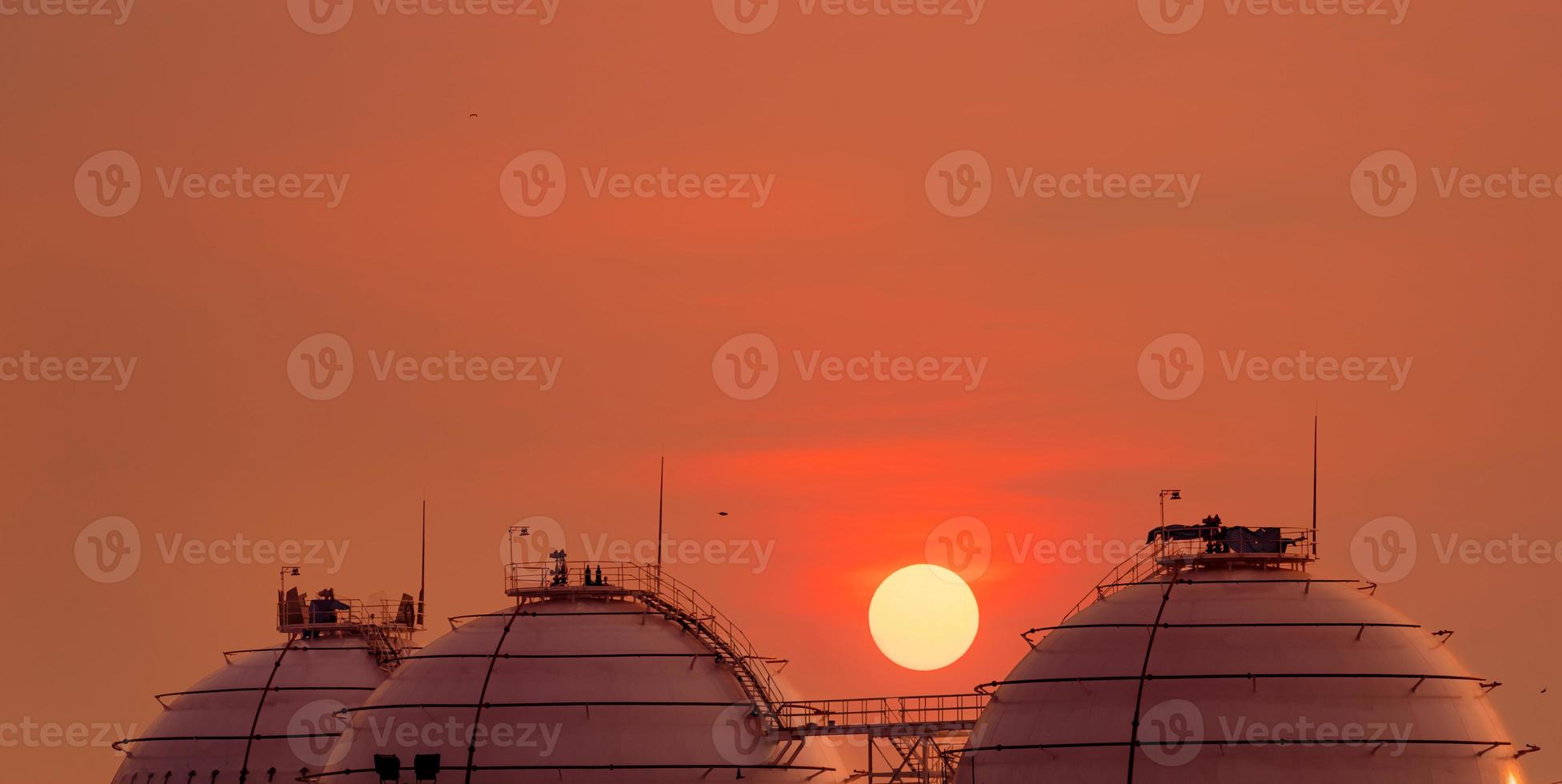 Industrial gas storage tank on orange sunset sky. LNG or liquefied natural gas storage tank. Spherical gas tank in petroleum refinery. Above-ground storage tank. Natural gas storage industry. photo