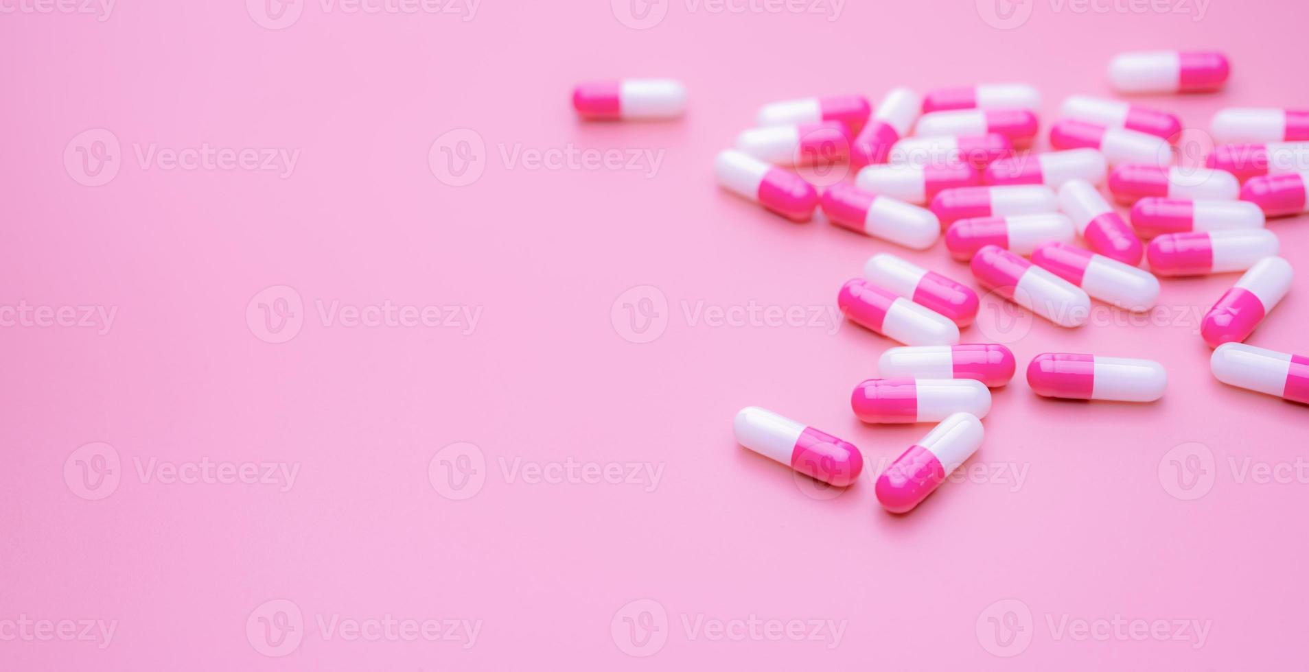 píldora de cápsulas antibióticas rosa-blancas esparcidas sobre fondo rosa con espacio. pancarta de farmacia. píldoras de cápsula antibiótica. fondo de pantalla de la tienda de farmacia. industria farmacéutica. fármacos antimicrobianos. cuidado de la salud. foto