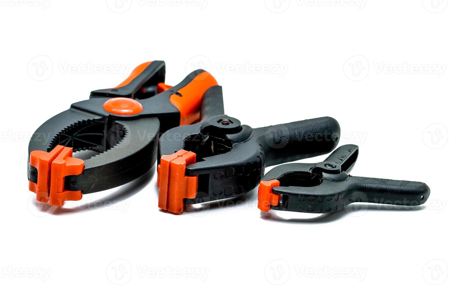 Black and orange spring clamp isolated on white background. Set of small, medium, and big size of plastic clamp. Clamping tools for carpentry work. Hand tools for handicraft. Clamping equipment. photo