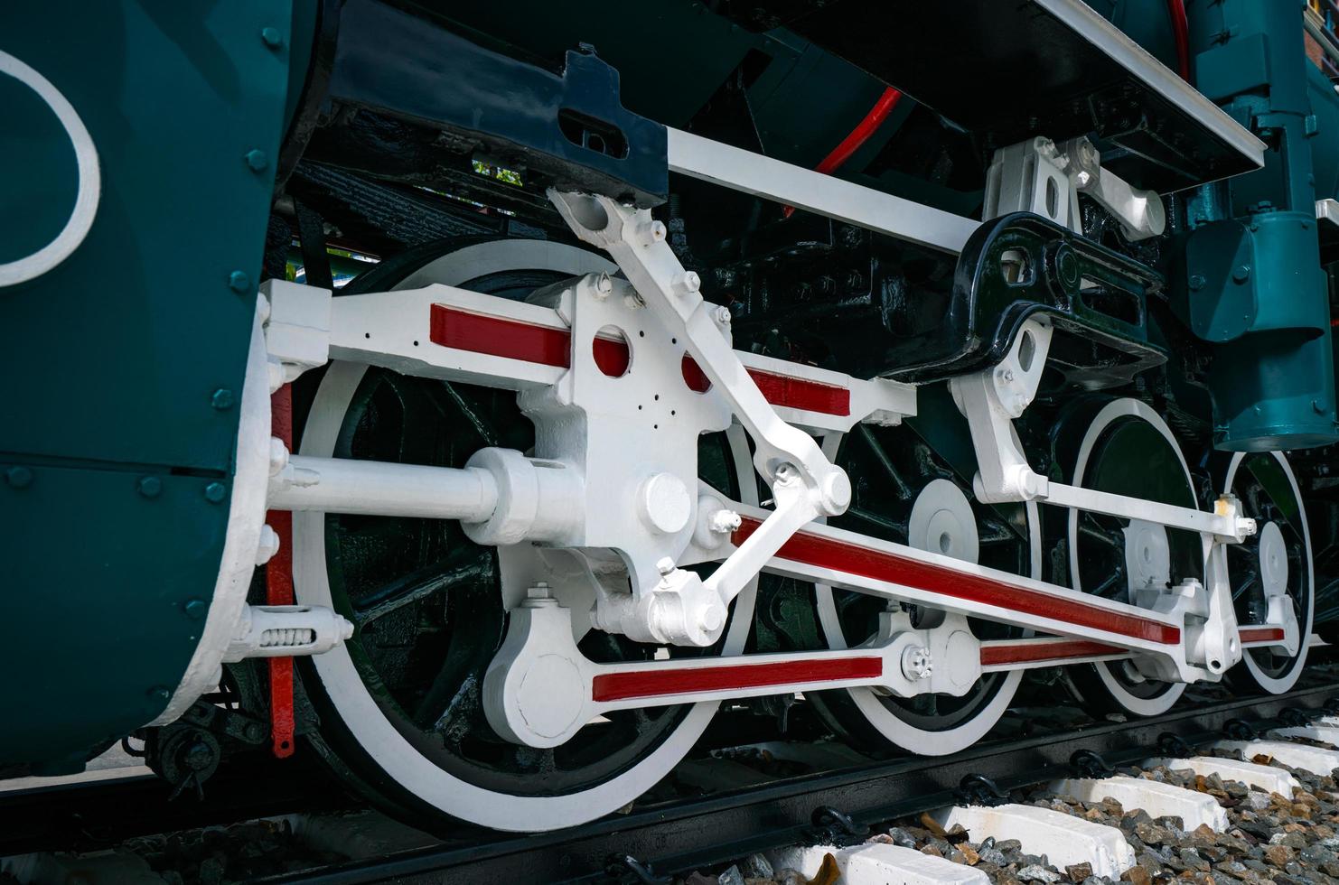 Closeup wheel of train. Green red and white train. Antique vintage train locomotive. Old steam engine locomotive. Black locomotive. Old transportation vehicle. photo