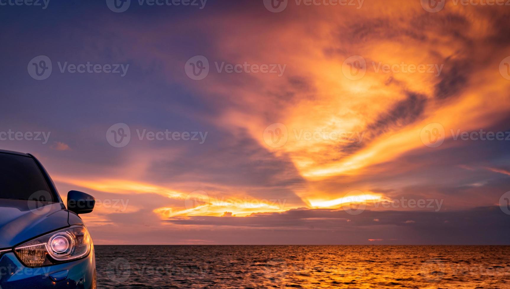 Blue compact SUV car with sport and modern design parked by beach at sunset. Hybrid and electric car technology. Car parking space. Automotive industry. Car care business background. Beautiful sky. photo