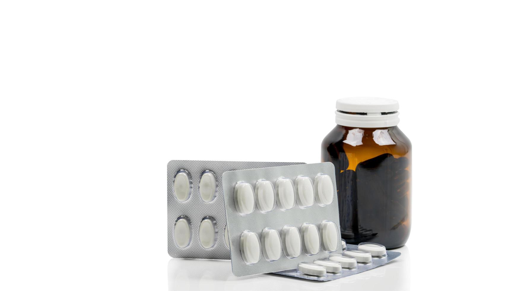 Vitamins capsule in amber glass bottle with blank label and supplements tablets in blister pack on white background. Antioxidants for healthy skin. Good supplement pills for woman bone. photo