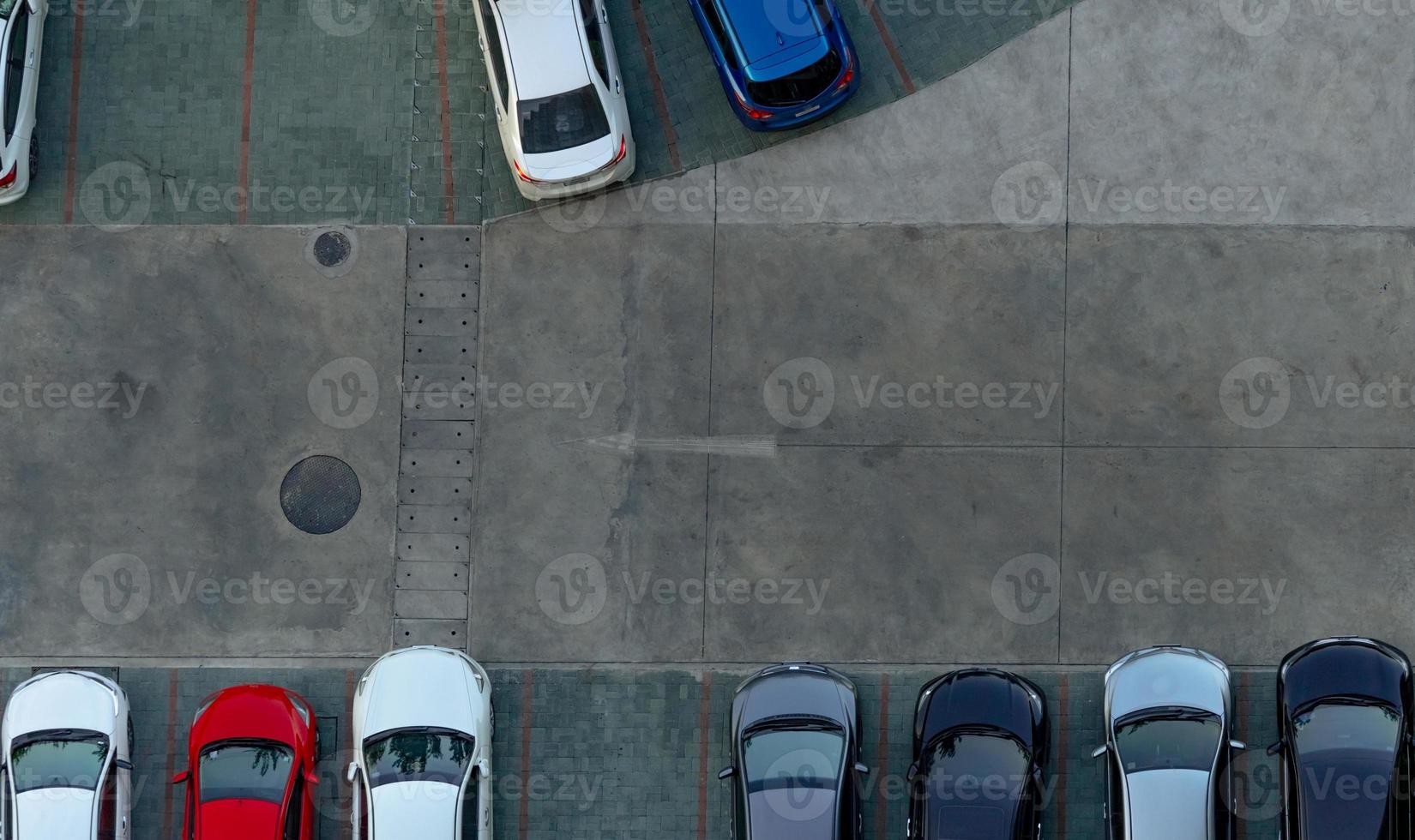 Top view concrete car parking lot. Aerial view of car parked at car parking area of apartment. Outdoor parking space with empty slot. One way traffic sign on road. Above view outside car parking lot. photo