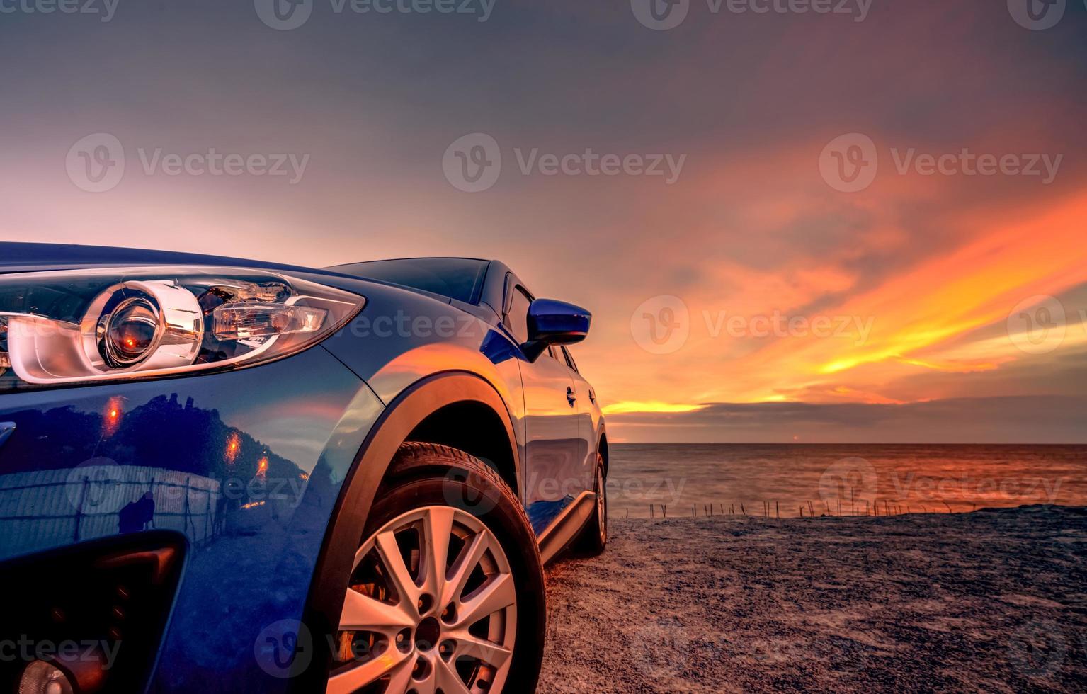 coche suv compacto azul con diseño deportivo y moderno estacionado en la playa al atardecer. tecnología de coches híbridos y eléctricos. plaza de aparcamiento. industria automotriz. antecedentes comerciales de cuidado de automóviles. cielo hermoso. foto