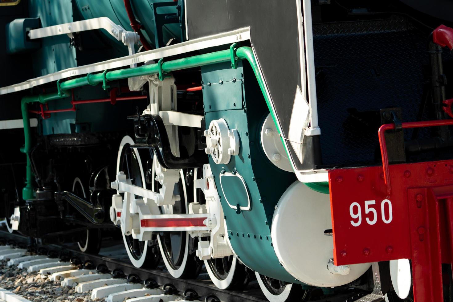 Closeup wheel of train. Green red and white train. Antique vintage train locomotive. Old steam engine locomotive. Black locomotive. Old transportation vehicle. Railway transportation industry. photo