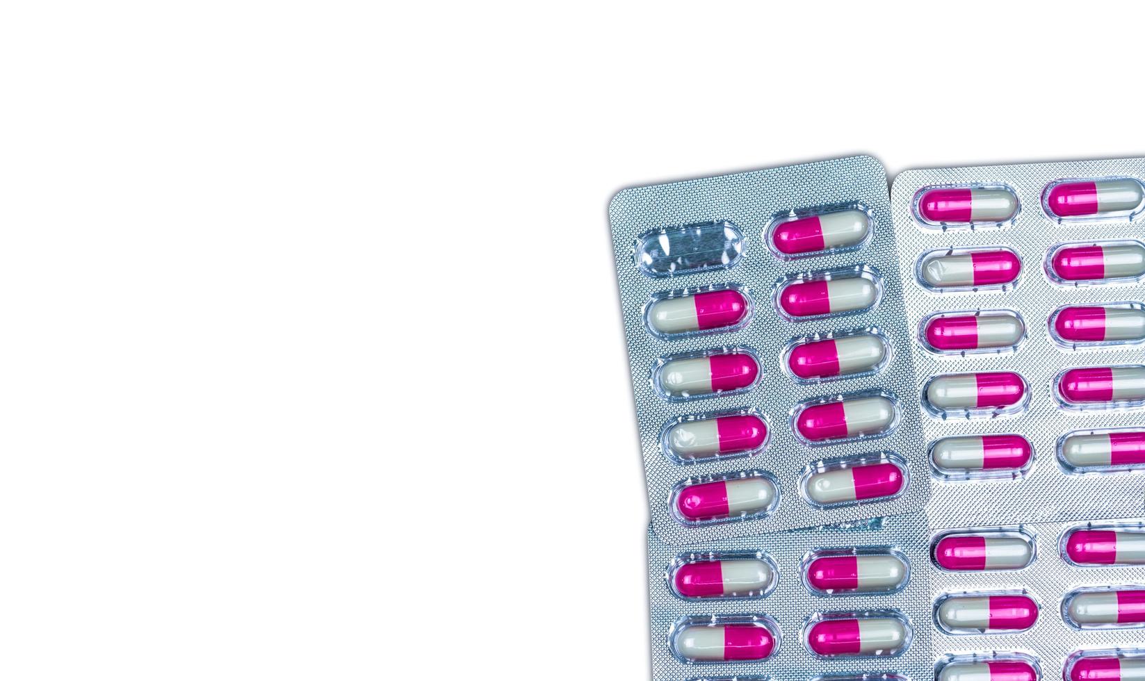 Quality control error in pharmaceutical manufacturing. Blister pack missing one capsule of antibiotic pill. Pink and white antimicrobial capsule pills isolated on white background with copy space. photo