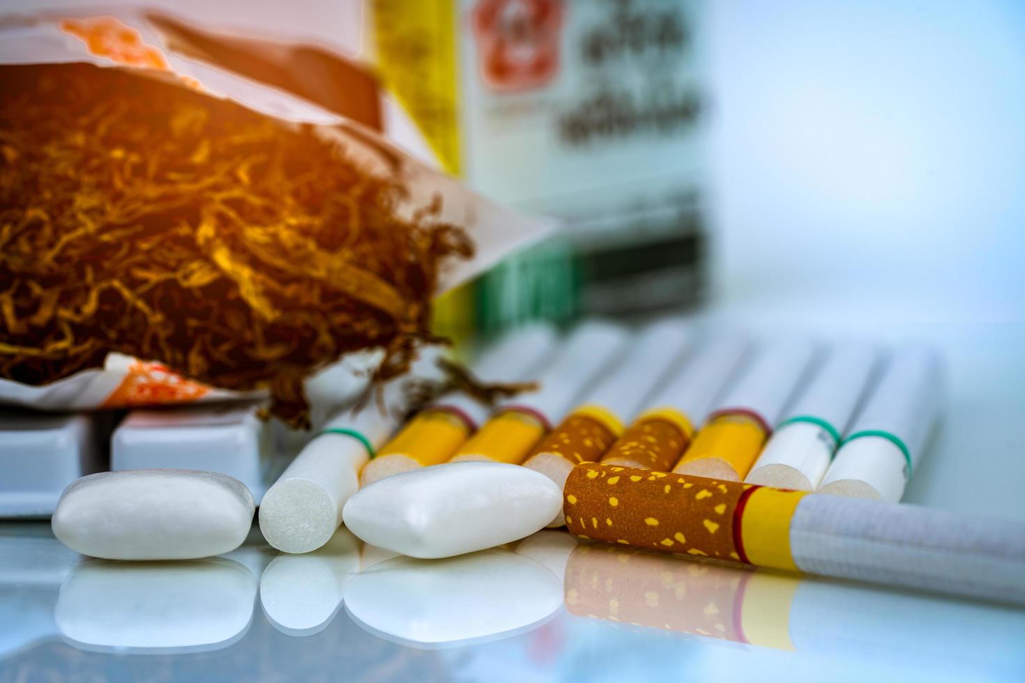 Nicotine chewing gum near pile of cigarettes and tobacco on white background with space. Quit smoking or smoking cessation and lung cancer concept. 31 May World no tobacco day. photo