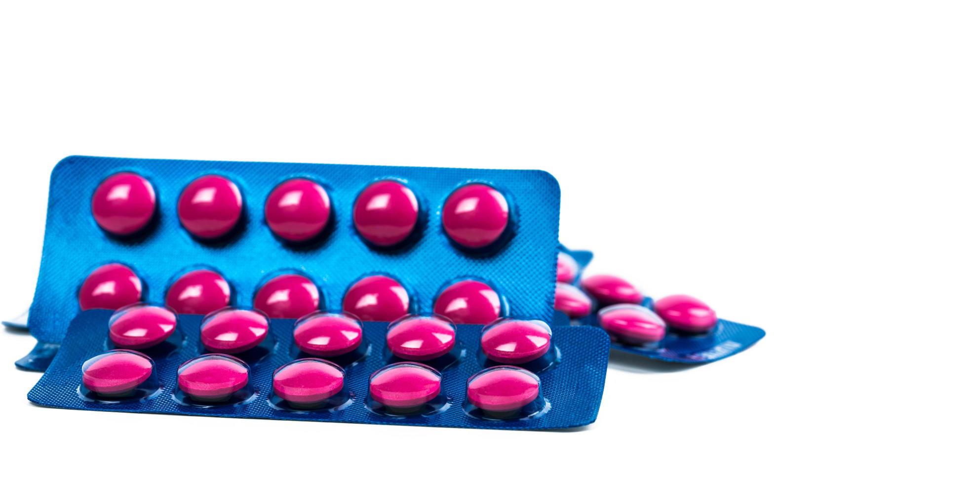 Píldora de tabletas de color rosa en blister azul aislado sobre fondo blanco. medicamento analgésico. industria farmacéutica. medicina para tratar la migraña, la fiebre, el dolor de muelas. productos de droguería de farmacia. foto