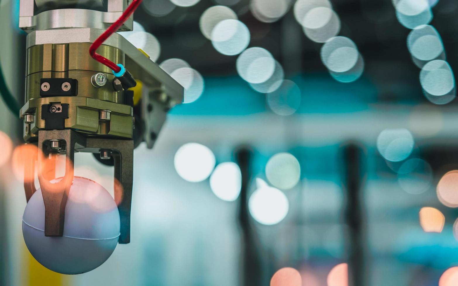 Closeup robot hand machine picking up white ball on bokeh blurred background. Use smart robot in manufacturing industry. Robotic tool in factory. Robot engineering concept photo