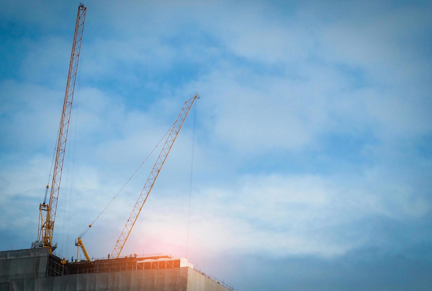 Construction crane on high-rise building with blue sky and white clouds. Construction site of commercial building or condominium or apartment in the city. Real estate business. Architecture background photo