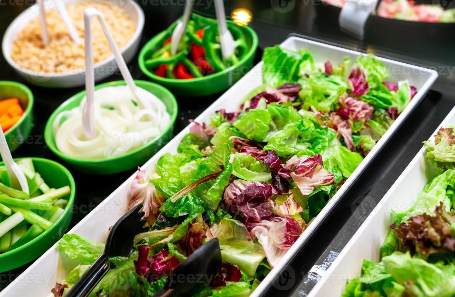 Salad bar buffet at restaurant. Fresh salad bar buffet for lunch or dinner. Healthy food. Fresh green and purple lettuce in white plate on counter. Catering food. Banquet service. Vegetarian food. photo