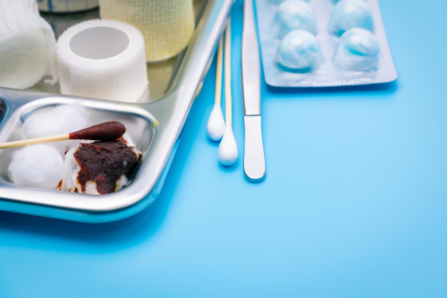 Wound care dressing set and stainless steel plate on blue background. Cotton ball and cotton stick with povidone-iodine for wounds, burns and cuts. Wound care supplies. Medical equipment for nurse. photo