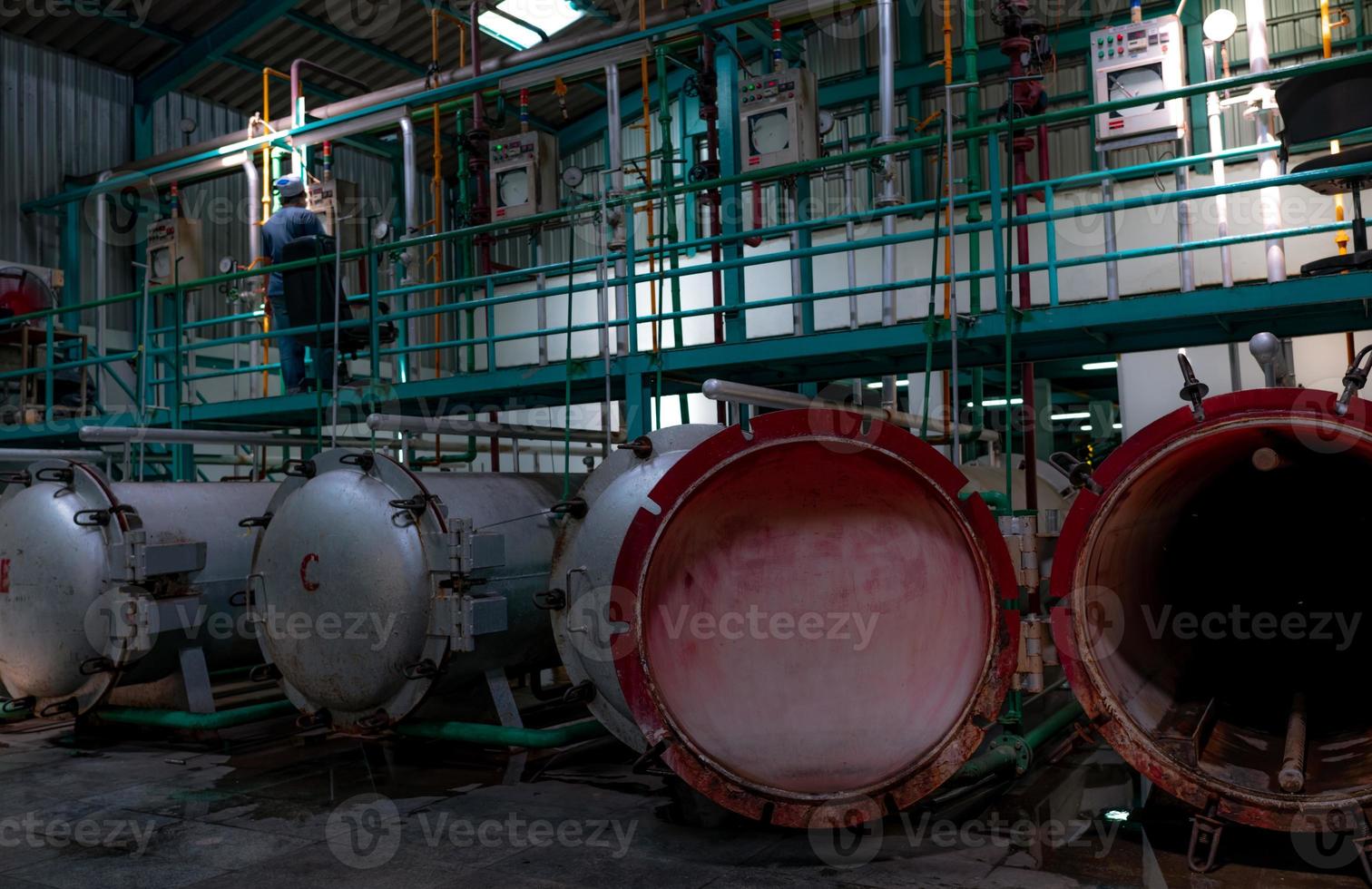 High pressure processing or high hydrostatic pressure machine. Metal tank in food manufacturing factory. Canned food reservoir for sterilizing. Worker working in factory to control pressure of machine photo