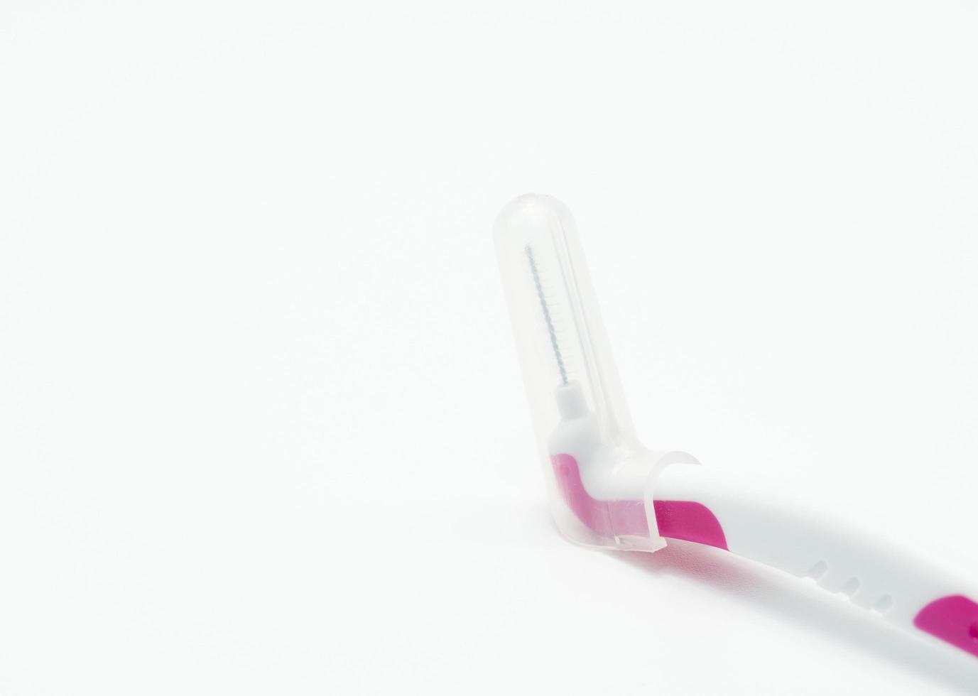 Interdental brush with white and pink plastic grip isolated on white background. Interdental toothbrushes for mouth hygiene. Braces brushes. Dental care or good dental hygiene concept. Medical tools. photo