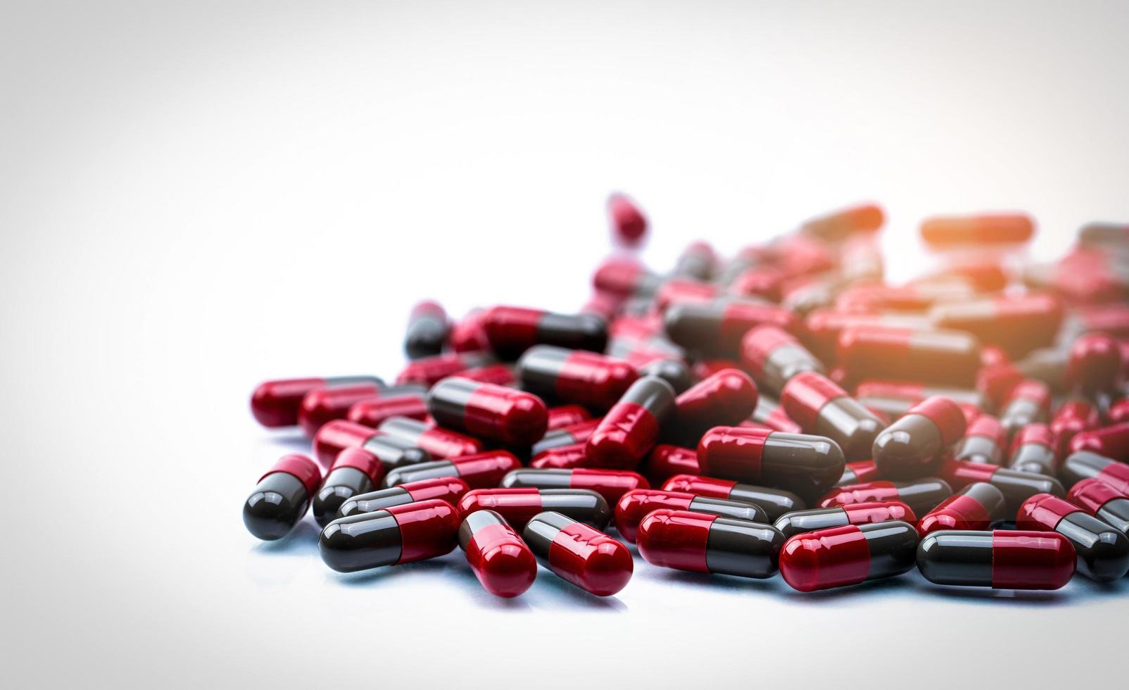 Selective focus of red-grey capsule pills on white background with space. Pharmaceutical industry. Pharmacy drugstore product. Pharmaceutical manufacturing. Pharmaceutics  Global healthcare concept. photo