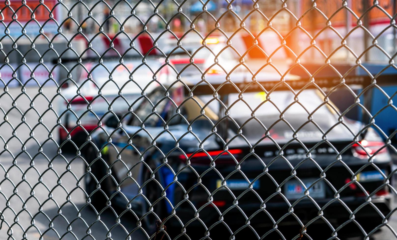 Motorsport car racing on asphalt road. View from the fence mesh netting on blurred car on racetrack background. Super racing car on street circuit. Automotive industry concept. photo