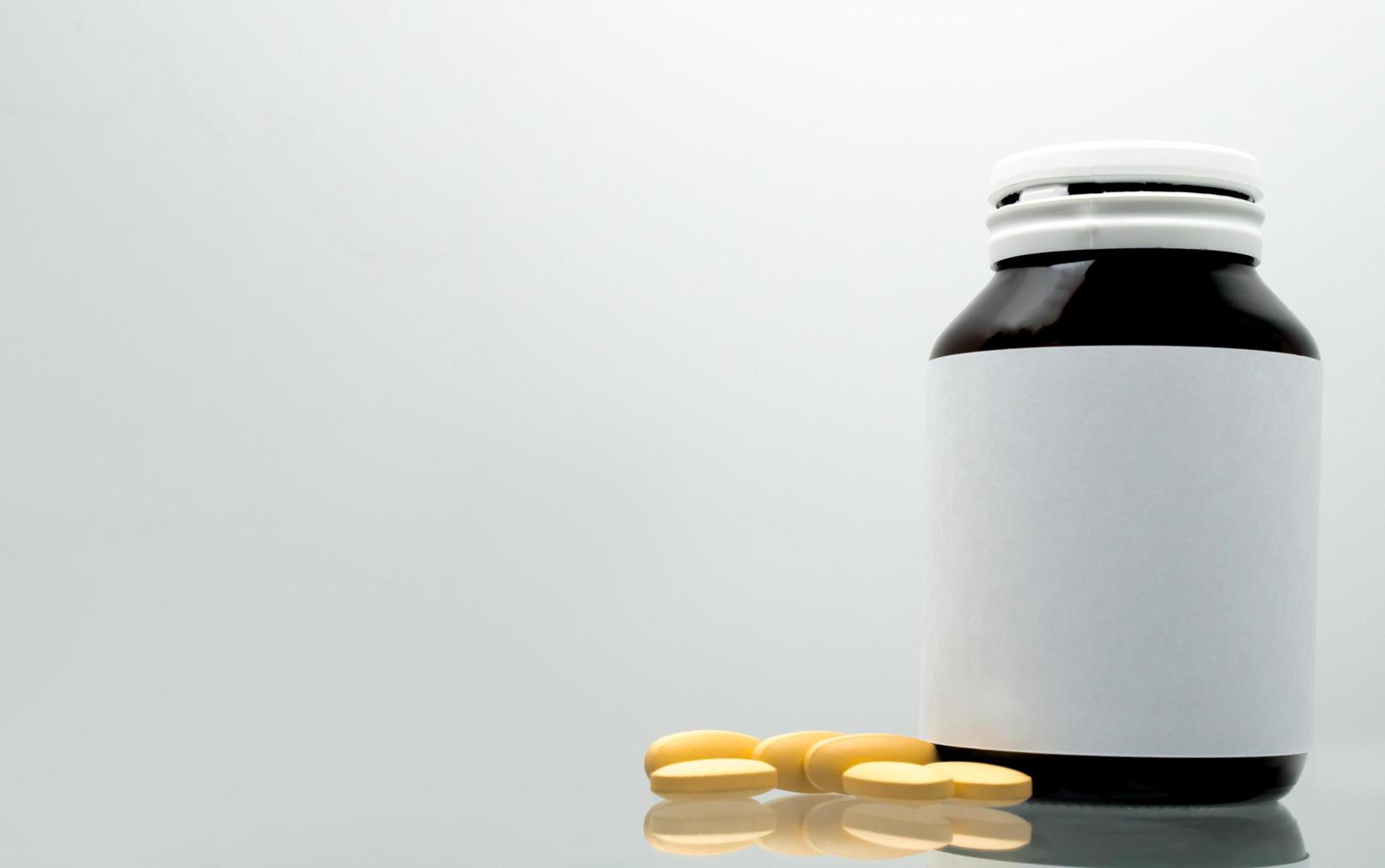 Tablets pills of vitamin C 1,000 mg on white background and amber bottle with blank label and copy space for text. Vitamin and supplement concept. Antioxidant photo