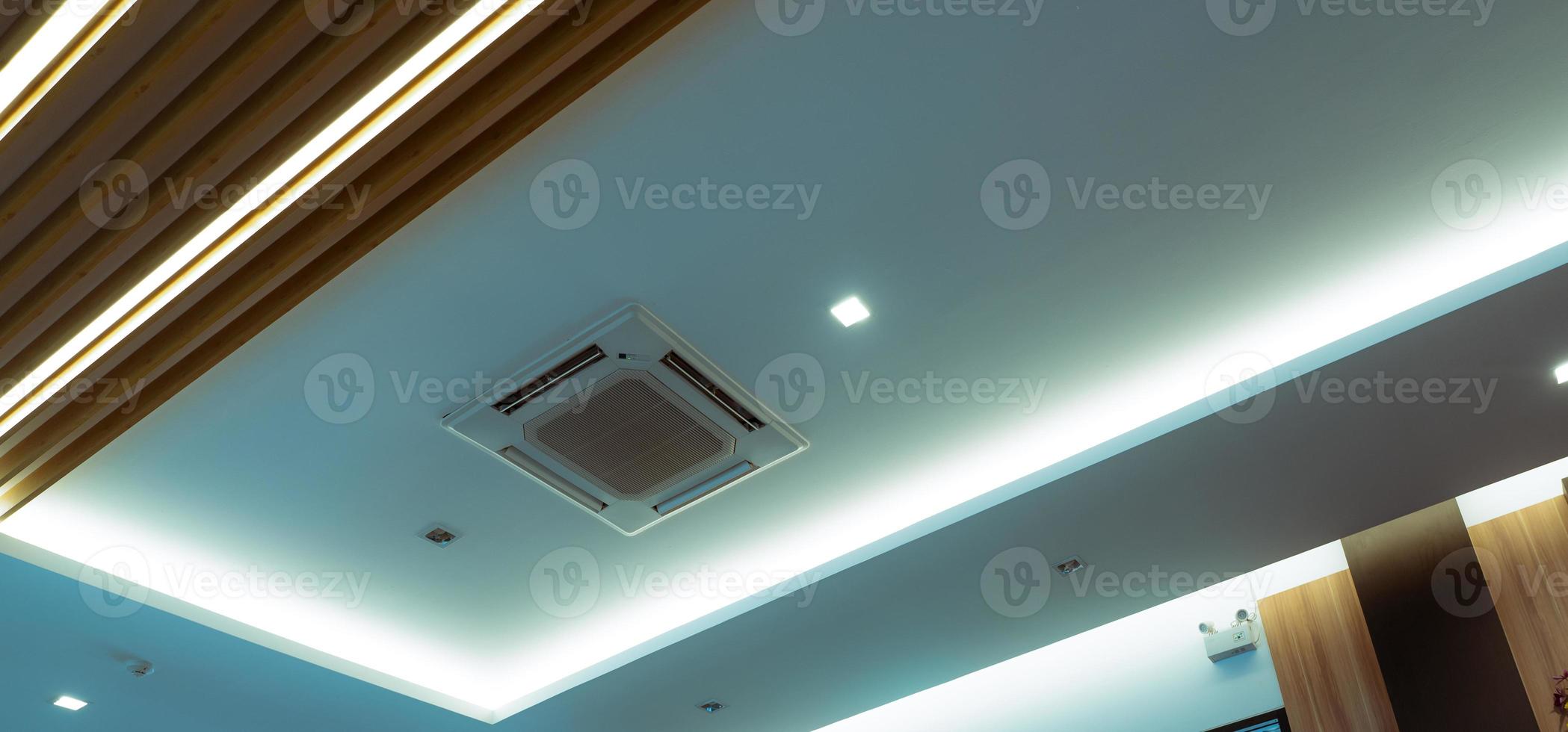 Selective focus on cassette type air conditioner mounted on ceiling wall. Air duct on ceiling in hotel. Air heading unit on gypsum wall. Cool system in the building. Air flow and ventilation system. photo